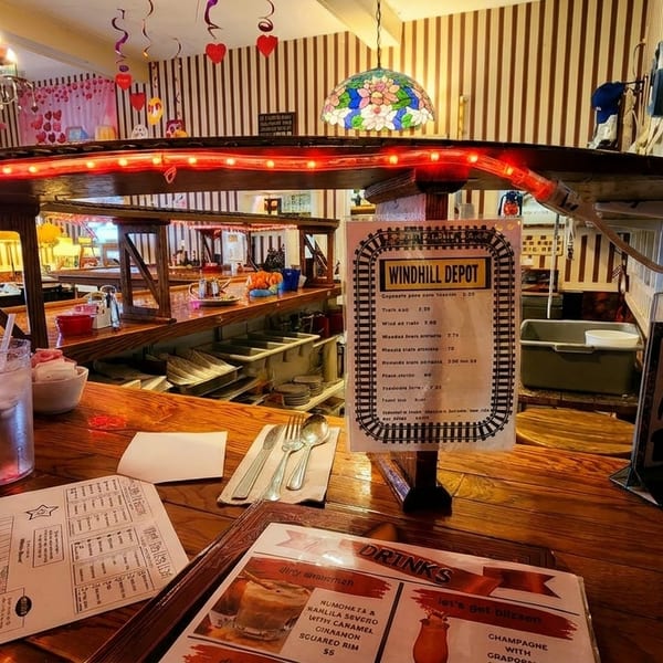 A rustic bar at Windhill Depot restaurant with menus, drinks, and train-themed decor.