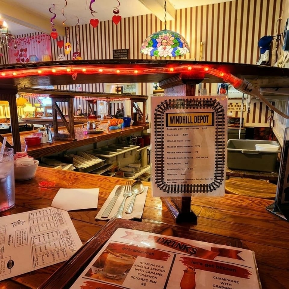 A rustic bar at Windhill Depot restaurant with menus, drinks, and train-themed decor.