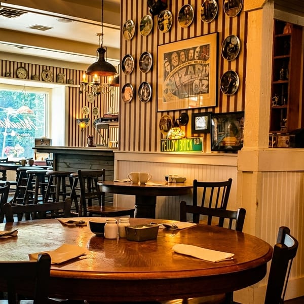 Cozy restaurant interior with striped walls, wooden tables, and a "Ham & Eggs" sign above a mirror.
