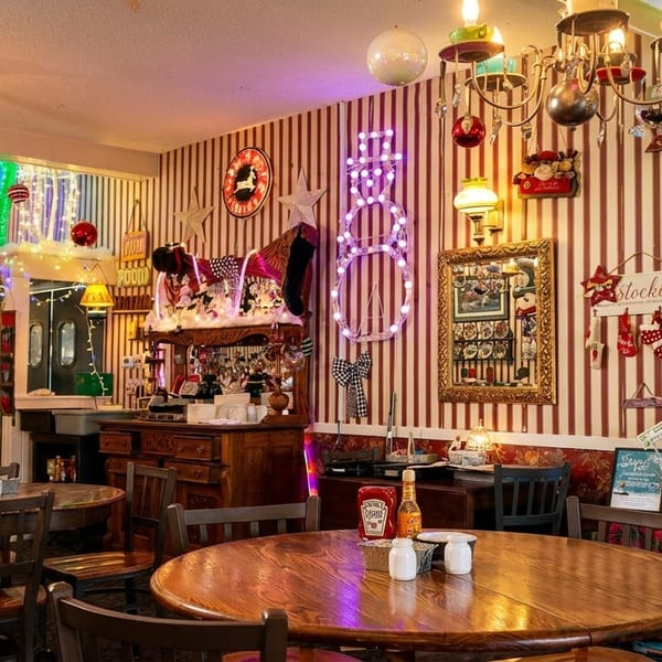 A cozy restaurant dining room decorated for Christmas with a man seated at a table.