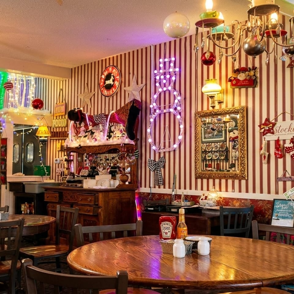 A cozy restaurant dining room decorated for Christmas with a man seated at a table.