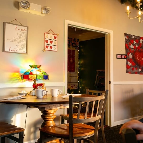A cozy restaurant interior with Valentine's Day decorations, a stained-glass lamp, and wooden tables.