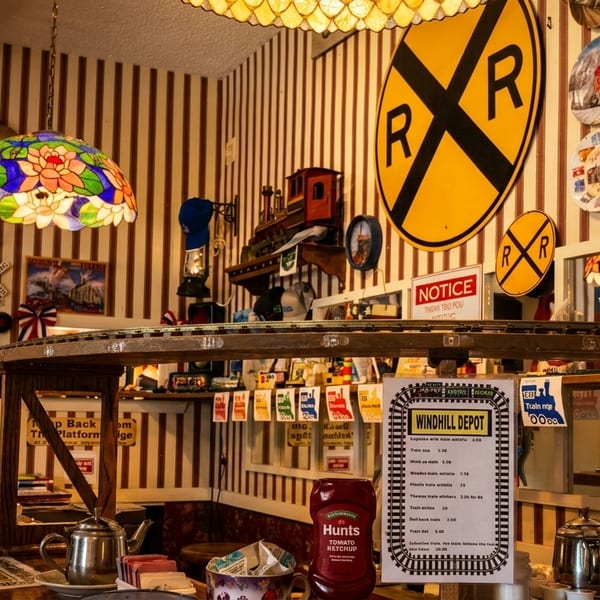 A diner interior with train-themed decor, including a model train track above the counter.