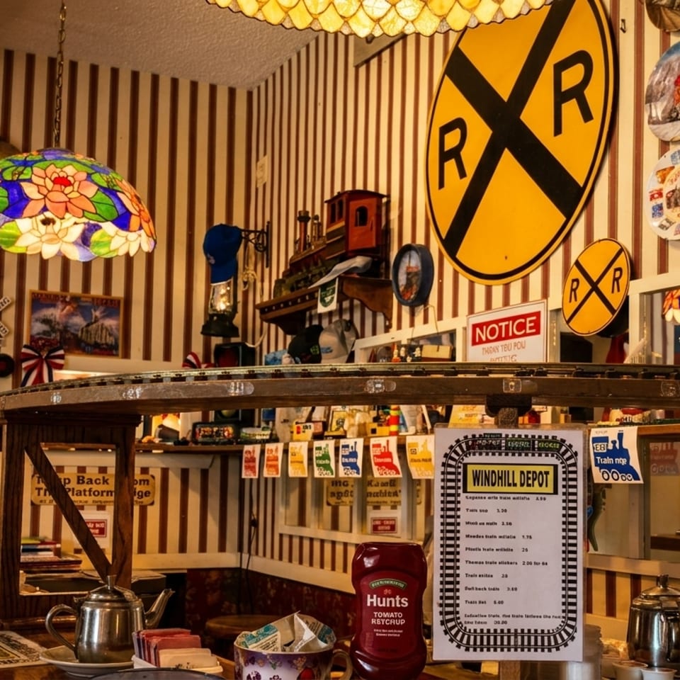 A diner interior with train-themed decor, including a model train track above the counter.