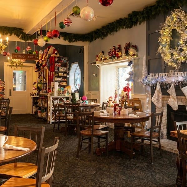 Restaurant dining room decorated for Christmas with wreaths, ornaments, stockings, and set tables.